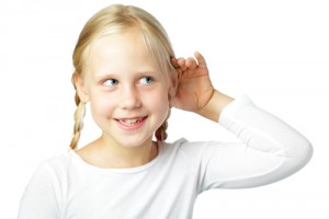 Una niña escucha con su mano en su oído